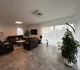modern furniture, leather sofa, coffee table, TV, white floor, large windows, indoor plants, curtains