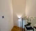 glass staircase, light on the wall, flower vase, wooden floor