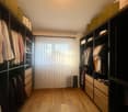 Wooden floor, tall wardrobes on either side, white curtains, natural light