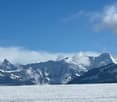 mountain range with snow, clear blue sky, fog, flat landscape