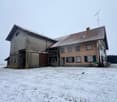 2 story house, grey facade, brown roof, large garage, surrounded by snow.