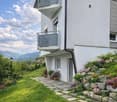 2 story house, white exterior, 2 balconies, stone pathway, garden with flowers, mountain view