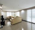 spacious living room, beige leather sofas, coffee table, TV, floor lamp, large windows, marble floor