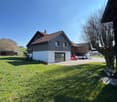 Detached house, brown roof, white walls, garage, cars parked in front, green lawn, trees
