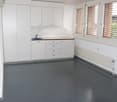 Empty room with kitchen, cupboards, sink, faucet, and windows with blinds.