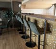 a room with bar counter, chairs, floor lamp, potted plant, round table