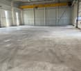 Large open warehouse space with concrete floor, metal framing, and an overhead crane visible.