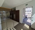 modern hallway, glass walls, staircase with metal railing, open door, light, parking spot visible