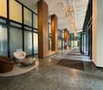 lobby area with modern design, wooden benches, glass walls, chandeliers, and a glass door