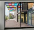 large windows, entrance with glass doors, parking lot, green bushes