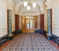 long hallway, wooden doors, ornate columns, tiled floor, chandelier