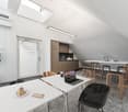 Sleek white walls, wood floor, modern white tables, laptop on a table, modern stools, indoor plant, modern kitchen, lamps