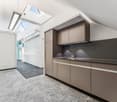 modern kitchen with gray cabinets, white walls, gray floor, skylights, sink, faucet, power outlet