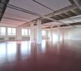 large open space, red floor, white walls, white ceiling, large windows, white pillars