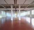 Empty room with white walls, red floor, white ceiling, large windows, white pillars, white radiators