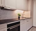 Modern kitchen with white cabinets, black countertops, Siemens appliances, and a potted plant on the counter