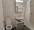 Tiled bathroom with a toilet, sink, vanity cabinet, and shower curtain