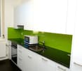 Modern kitchen with white cabinets, green glass backsplash, granite countertop, and a dishwasher