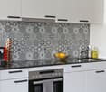 modern kitchen, white cabinets, patterned backsplash, black countertops, oven, sink, faucet, dishwasher, coffee machine, bowl of lemons