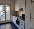 kitchen with white cabinetry and modern appliances, black tiled flooring, double doors leading to a balcony