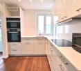 White cabinets, modern appliances, tiled floor, wooden countertop, built-in ovens, under cabinet lights