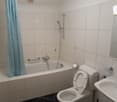 The image shows a bathroom with a bathtub, shower, toilet, and tiled walls and floor.
