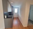 modern kitchen, wooden floor, gray cabinets, black countertop, stainless steel sink, faucet, window