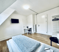 bedroom with bed, desk, chair, TV, radiator, door, wardrobe, lamp, telephone