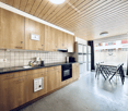 wooden cabinets, tiled backsplash, dishwasher, washing machine, black countertops, oven, sink, faucet, tile flooring