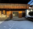 Building: raised ground floor, wooden doors, brick walls, snowy area, chimney, adjacent building, front balcony