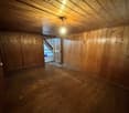 bare room with wooden floor, wooden paneling on walls, single light fixture in the ceiling