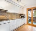 kitchen with white cupboards, granite countertop, dishwasher, gas stove, coffee machine, balcony with table and chairs