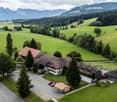 aerial view, 3 buildings, brown roof, green valley, parking lot, mountains