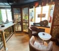 small room, wooden floor, wall-mounted guitars, glass walls, leather chairs, center table