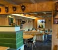 wooden walls, wooden tables, green cushioned seating, chairs, antlers and carved figures on the wall