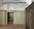 vaulted ceiling, arched doorway, wooden wardrobe, arched window, unfinished floor