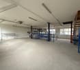 Wide and empty room, industrial, empty, white walls, bare floor, some shelves, windows