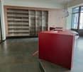 empty room, wooden cabinets, glass shelves, red desk, glass door, gray floor, large window