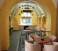 yellow walls, arched ceiling, round tables, chairs, chandelier, bar stools