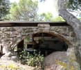 House made from stone, stone arch entrance, open kitchen, natural surroundings