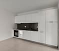 Modern, minimalist kitchen with white cabinets, black countertops, built-in oven, and dishwasher