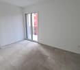 Spacious bedroom with white walls, large windows, and gray tile flooring.