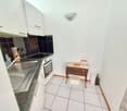 white cabinets, tile floor, stainless steel sink, black countertop, white oven, small wooden table