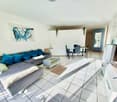 Living room with sofa, coffee table, dining table, chairs, television, artwork
