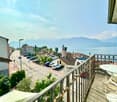 Balcony with railings, table and chairs, view of the street and lake
