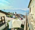 balcony, white umbrella, view of the lake and mountains, cars parked on the street