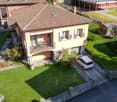 2-story house with red tile roof, yellow exterior walls, balcony, garden, and parking space