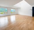 Spacious living room with large windows offering a scenic view of the surrounding mountains, hardwood flooring, and a bright, open layout