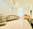 white walls, tiled floor, couch with pillows, wooden cabinet, plants