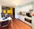 white cabinets, oven, dishwasher, refrigerator, sink, faucet, table with laptop, fireplace, kitchen fan, clock